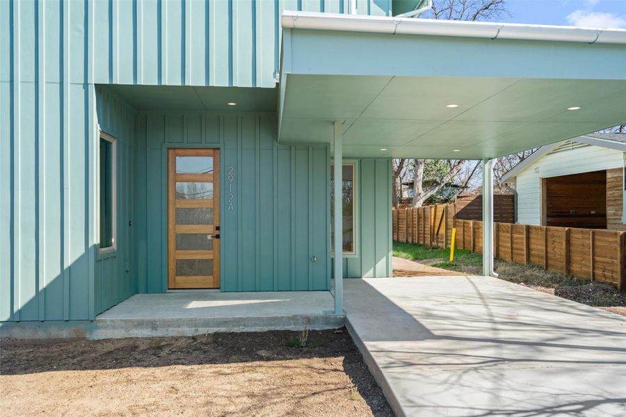 Doorway to property with board and batten siding and fence