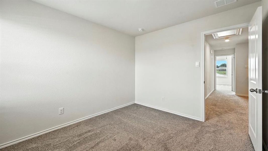 Interior room featuring neutral wall paint, gray carpet flooring, white baseboards, and a white interior door with dark hardware
