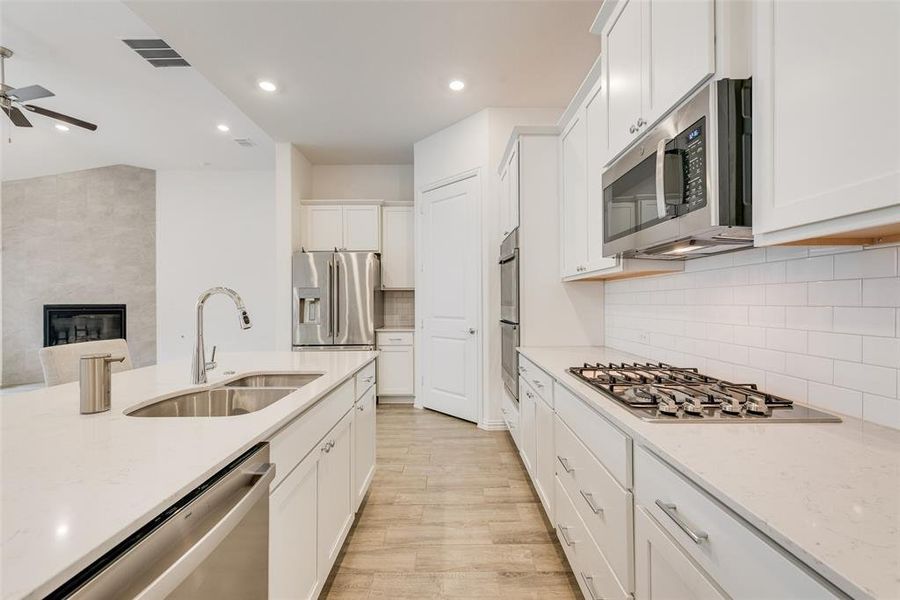Kitchen with appliances with stainless steel finishes, ceiling fan, white cabinetry, recessed lighting, and light wood finished floors Kitchen with appliances with stainless steel finishes, ceiling fan, white cabinetry, recessed lighting, and light wood finished floors