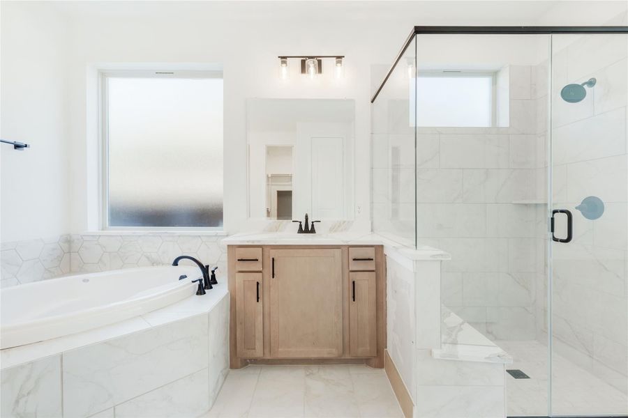 Master bathroom with soaking tub, glass walk-in shower, and wood vanity with marble tile surround