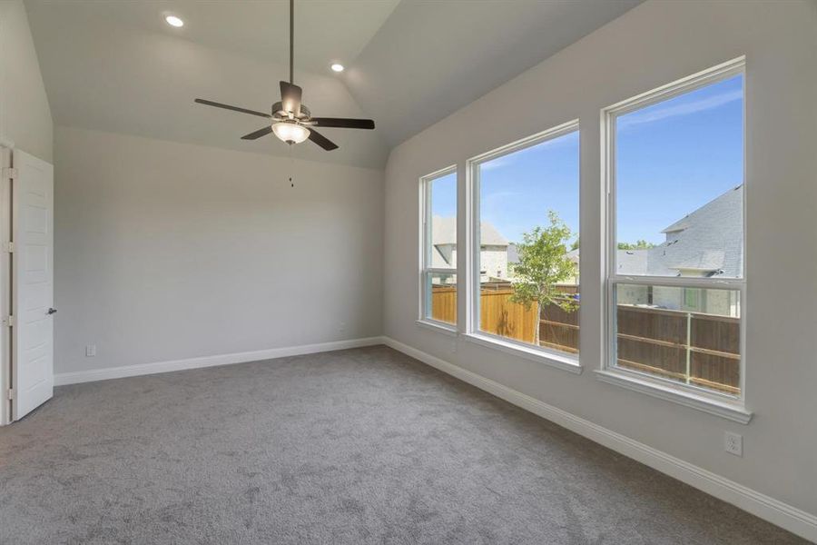 Carpeted empty room featuring ceiling fan and lofted ceiling