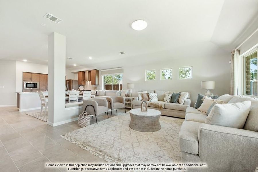Open-concept living room with neutral sofas and tile floors, open to kitchen and dining area in background