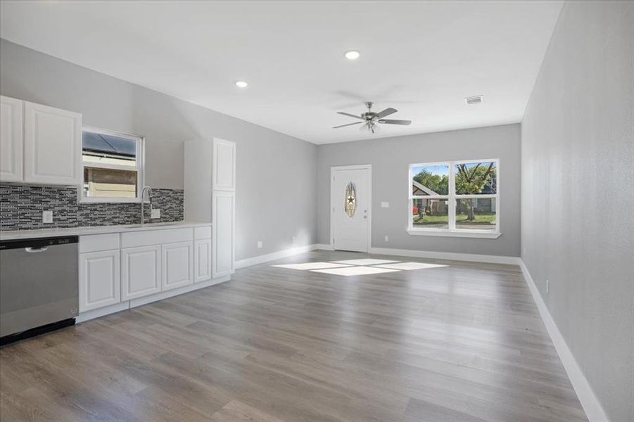 Kitchen with dishwasher, sink, white cabinetry, light hardwood / wood-style flooring, and ceiling fan