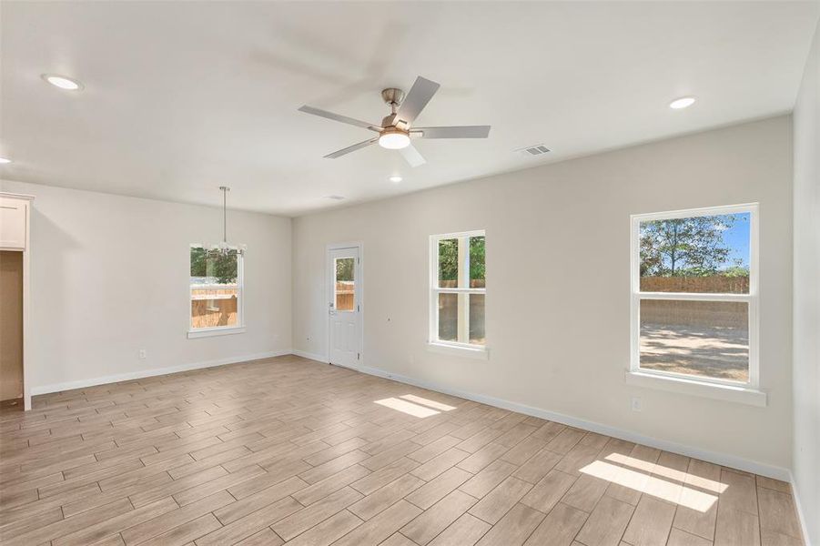 Spacious room featuring wood-finish flooring, recessed lighting, and a ceiling fan Spacious room featuring wood-finish flooring, recessed lighting, and a ceiling fan