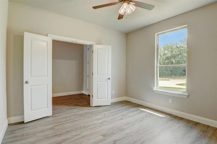 Unfurnished bedroom featuring light wood-type flooring, baseboards, and a ceiling fan