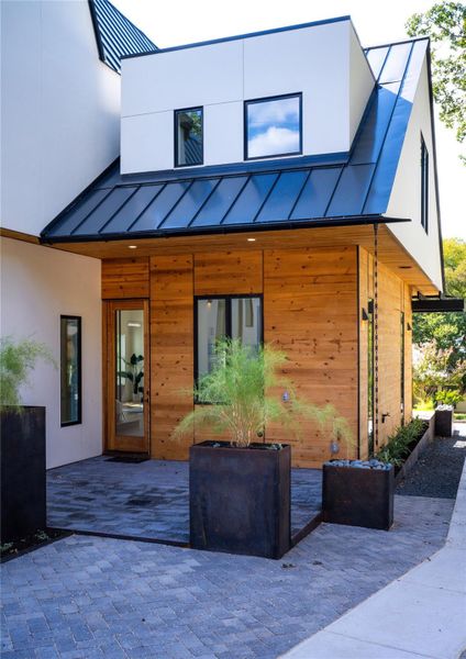 Rear view of property with a standing seam roof, stucco siding, and a patio