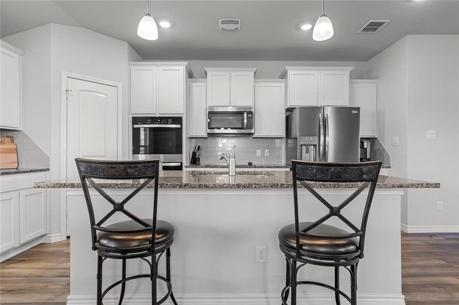 Kitchen with decorative backsplash, white cabinets, and a kitchen bar