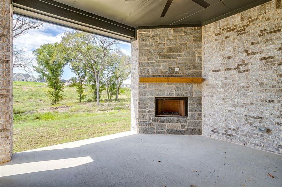 View of covered patio with ceiling fan and an outdoor stone fireplace View of covered patio with ceiling fan and an outdoor stone fireplace