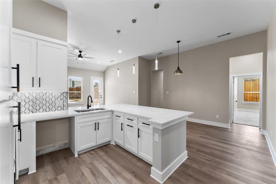 Kitchen with white cabinetry, sink, pendant lighting, and hardwood / wood-style flooring