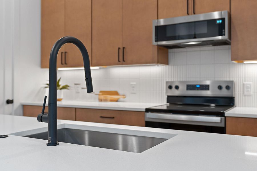 Kitchen with appliances with stainless steel finishes, tasteful backsplash, brown cabinets, and modern cabinets Kitchen with appliances with stainless steel finishes, tasteful backsplash, brown cabinets, and modern cabinets