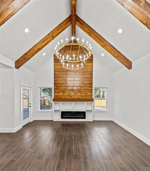 Unfurnished living room with beam ceiling, dark wood-style floors, a chandelier, high vaulted ceiling, and recessed lighting Unfurnished living room with beam ceiling, dark wood-style floors, a chandelier, high vaulted ceiling, and recessed lighting