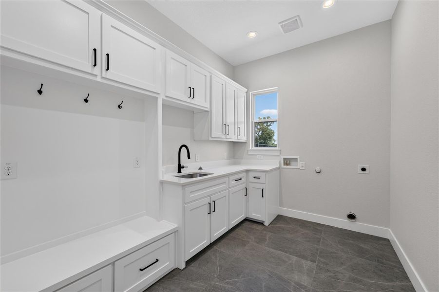Functional utility space features durable tile flooring alongside built-in cabinetry and a utility sink.