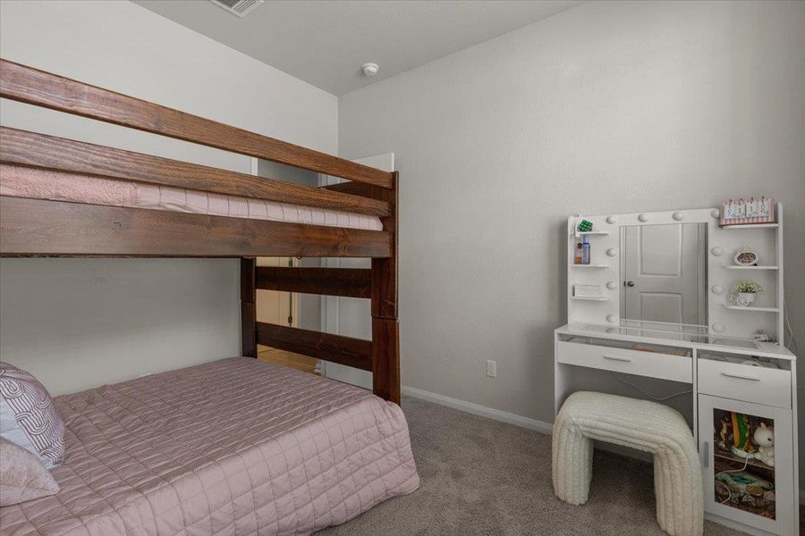 Smooth walls and soft carpeting define this cozy and inviting secondary bedroom space.
