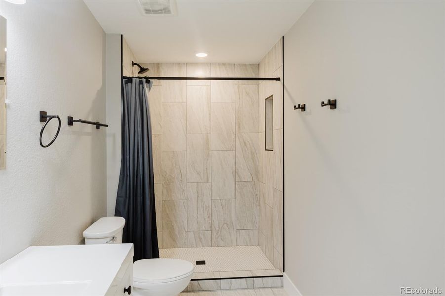 This gorgeous tile shower has a tile inset. Black plumbing accents add the perfect extra touch. This gorgeous tile shower has a tile inset. Black plumbing accents add the perfect extra touch.
