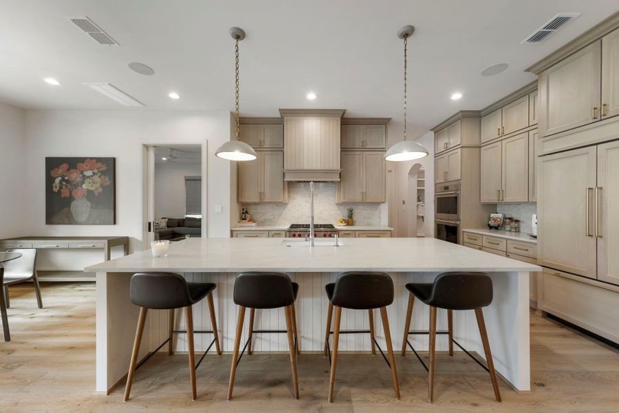 Luxurious chef’s kitchen featuring a dramatic oversized marble island with seating, custom floor-to-ceiling cabinetry with refined millwork and designer brass hardware, Wolf appliances, and a Sub-Zero built-in refrigerator—beautifully designed for elevated everyday living and sophisticated entertaining.