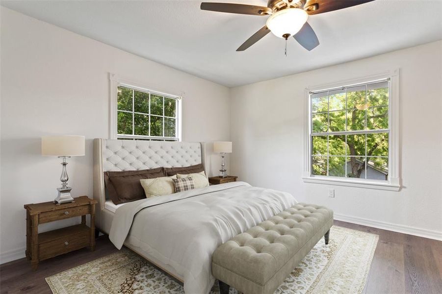 Bedroom featuring multiple windows, baseboards, and wood finished floors