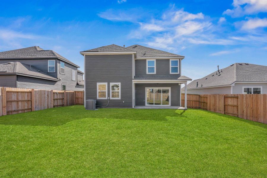 A spacious, verdant yard with a privacy fence backs onto a contemporary home featuring a covered patio. A spacious, verdant yard with a privacy fence backs onto a contemporary home featuring a covered patio.