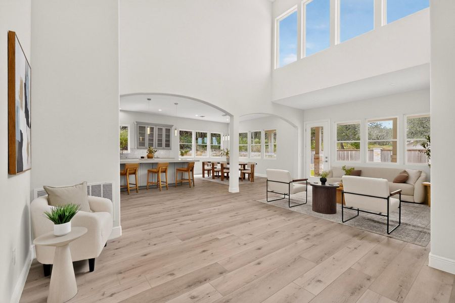 Double-height ceilings and arched transitions define this open-concept layout with wide-plank wood flooring.
