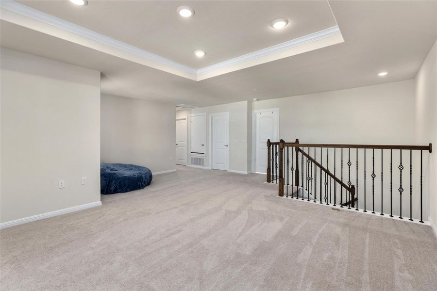 Spare room with a tray ceiling, crown molding, light carpet, and recessed lighting