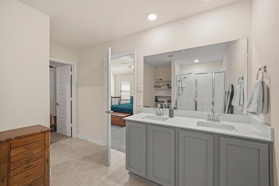 Full bath featuring double vanity, a stall shower, and ensuite bath Full bath featuring double vanity, a stall shower, and ensuite bath