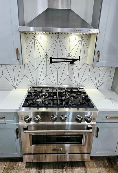 Stainless steel gas range and pot filler above.