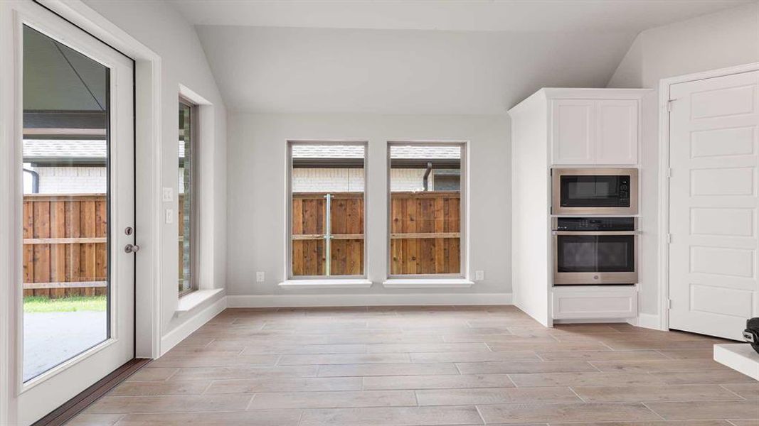 Unfurnished dining area with light hardwood / wood-style floors and vaulted ceiling