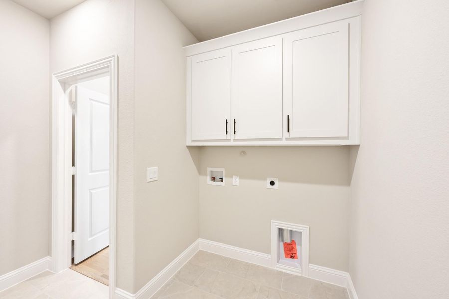 Laundry room with white upper cabinets, washer and dryer hookups, and tile flooring