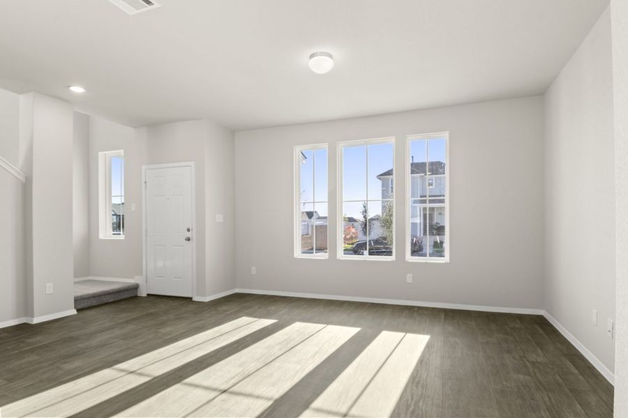 Image of a living room with dark vinyl flooring, light grey walls and three front windows