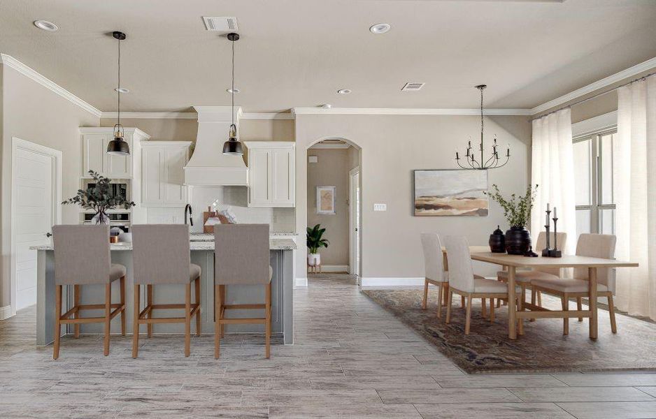 Kitchen with a breakfast bar area, crown molding, hanging light fixtures, white cabinetry, and custom exhaust hood