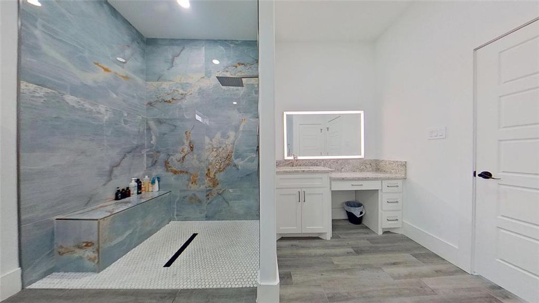 Spacious bathroom featuring a walk-in shower with blue-hued stone wall tiling and an integrated bench Spacious bathroom featuring a walk-in shower with blue-hued stone wall tiling and an integrated bench