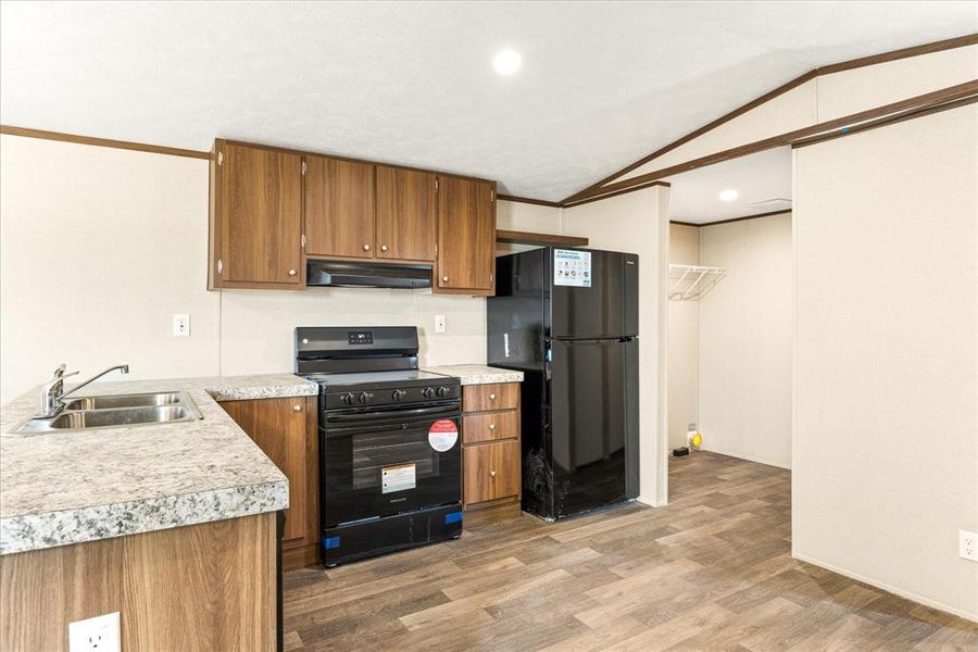 Kitchen featuring wood-finish cabinetry, granite-look countertops, and wood-finish flooring
