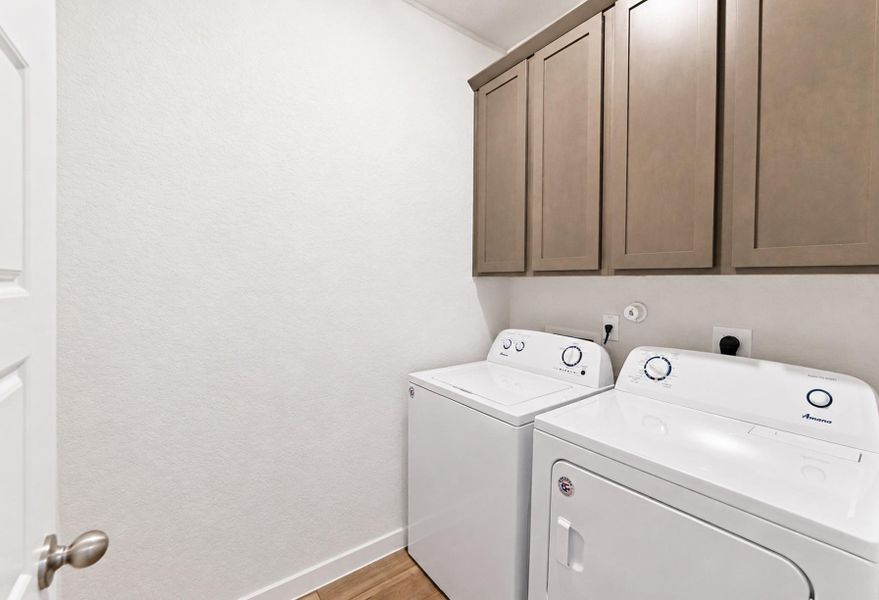 Ample overhead cabinetry complements the dedicated laundry space with wood-style flooring. Ample overhead cabinetry complements the dedicated laundry space with wood-style flooring.