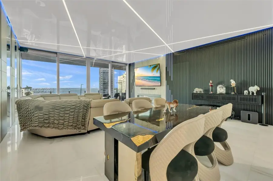 High-gloss ceiling featuring integrated linear lighting, expansive floor-to-ceiling windows, polished tile flooring, and a floor-to-ceiling fluted wall accent High-gloss ceiling featuring integrated linear lighting, expansive floor-to-ceiling windows, polished tile flooring, and a floor-to-ceiling fluted wall accent