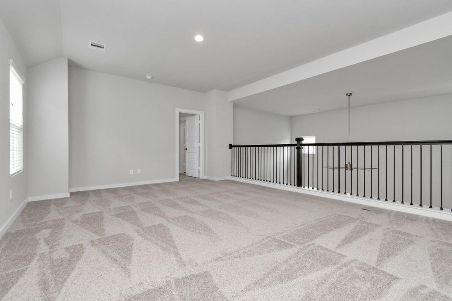 Ascend to relaxation in this fantastic game room! Ideal for both casual gatherings and adult gaming, it boasts plush carpet, lofty ceilings, custom paint, and ample windows for abundant natural light. Sample photo of completed home with similar floor plan. Actual colors and selections may vary.