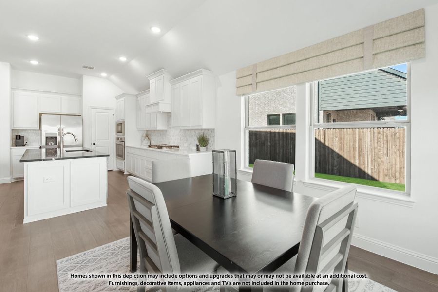 Dining area with dark table and gray chairs open to white kitchen with island and hardwood floors Dining area with dark table and gray chairs open to white kitchen with island and hardwood floors