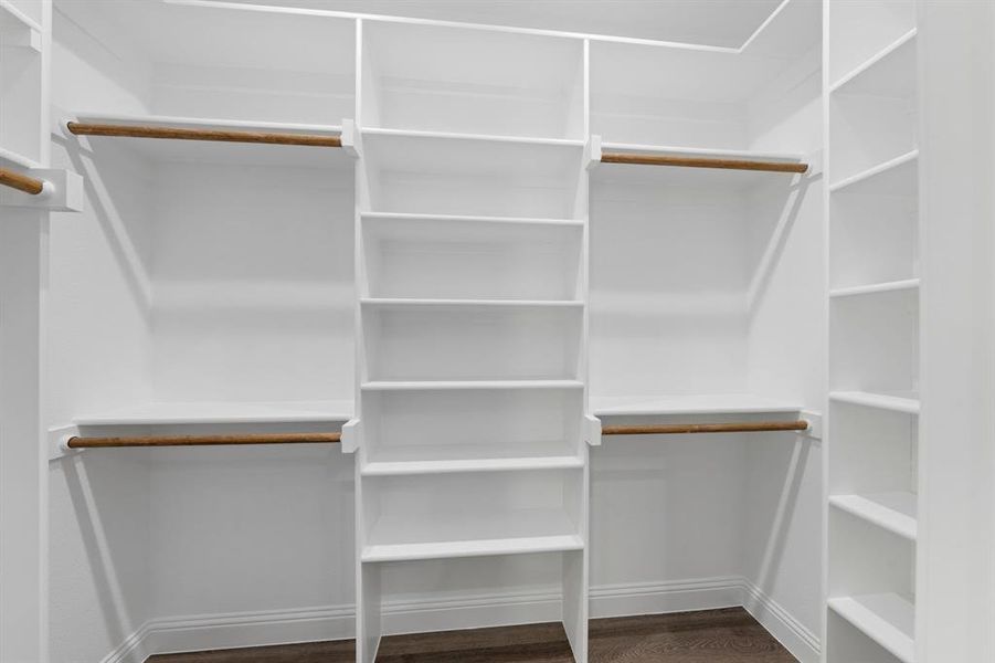 Walk in closet with dark wood-style floors