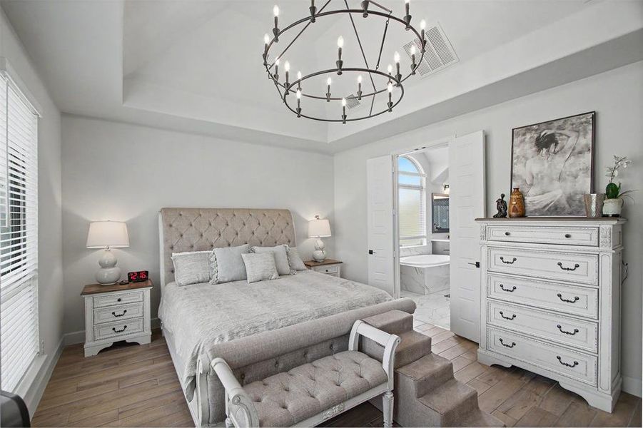 High ceilings featuring a tray design and a large circular chandelier