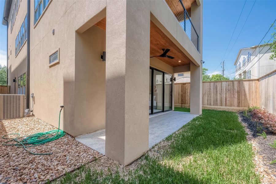 This is a modern two-story home with a covered entrance featuring a wooden ceiling and a fan. The house has a beige stucco exterior, and there's a neatly manicured lawn with a privacy fence. The pathway to the door is a mix of pebble and paved surfaces, creating a welcoming approach to the home. This is a modern two-story home with a covered entrance featuring a wooden ceiling and a fan. The house has a beige stucco exterior, and there's a neatly manicured lawn with a privacy fence. The pathway to the door is a mix of pebble and paved surfaces, creating a welcoming approach to the home.