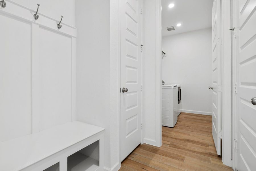 Functional mudroom area with a built-in bench and storage cubbies, conveniently located near the laundry room with additional cabinetry. Functional mudroom area with a built-in bench and storage cubbies, conveniently located near the laundry room with additional cabinetry.