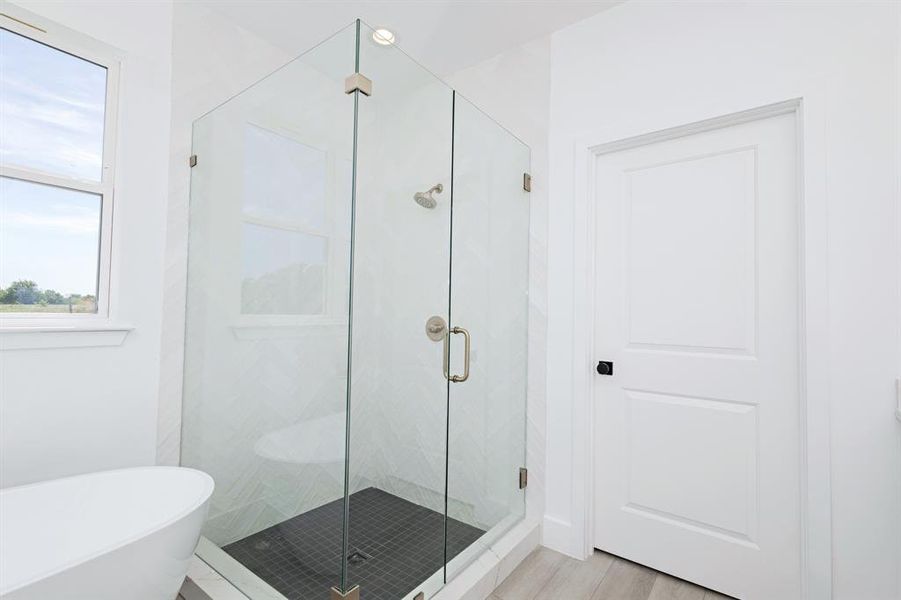 Bathroom featuring a freestanding tub, a shower stall, and wood finished floors