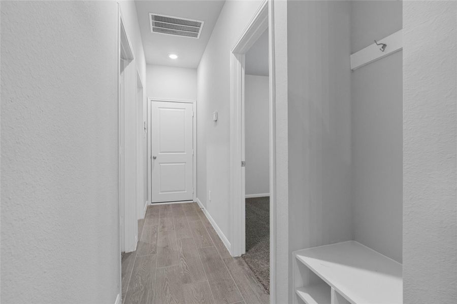 This dedicated area features a custom built-in bench with hooks, perfect for organizing coats, bags, and shoes right off the main hallway, keeping the rest of the home tidy.