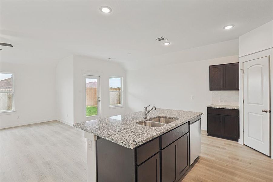 Kitchen with sink, light wood-type flooring, a center island with sink, and dishwasher