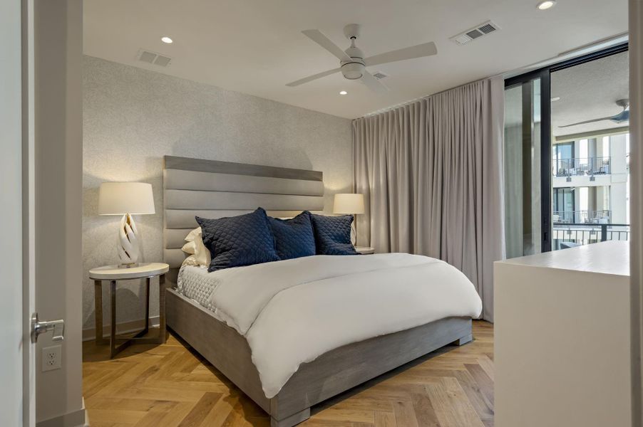Herringbone hardwood floors extend to a private balcony in this primary bedroom suite.