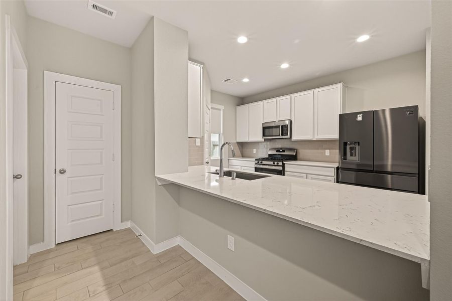 An additional view of the kitchen shows the layout and closed doors that lead to primary bedroom.