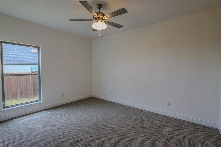 Spare room featuring dark colored carpet, ceiling fan, and baseboards