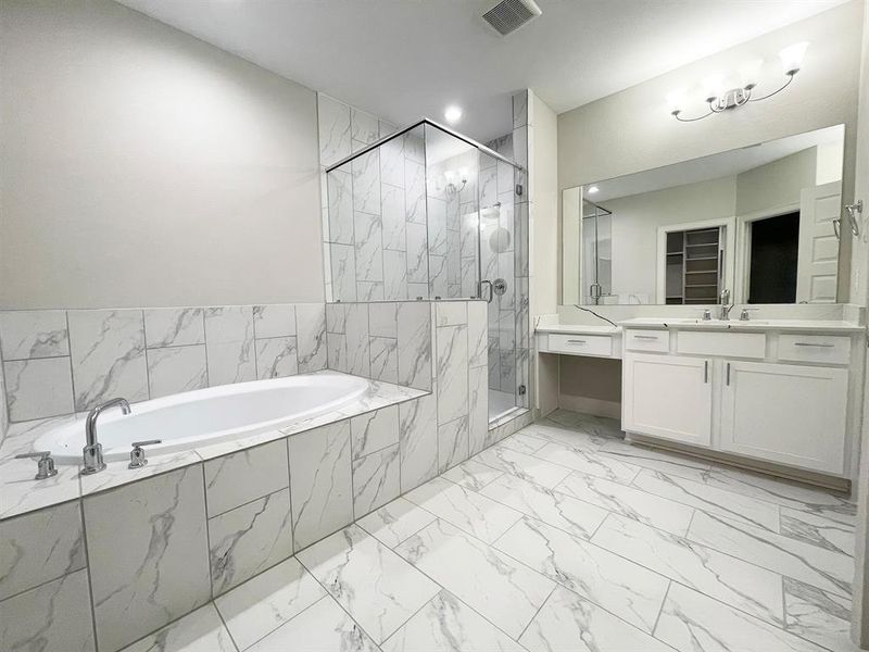 The ROClake's primary bathroom features a large shower and bathtub and dual vanities. The bright lighting fixtures and clean lines contribute to a serene, spa-like atmosphere.