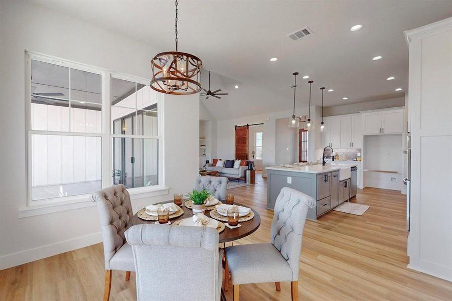 Dining space featuring lofted ceiling, a barn door, light hardwood / wood-style flooring, and a wealth of natural light