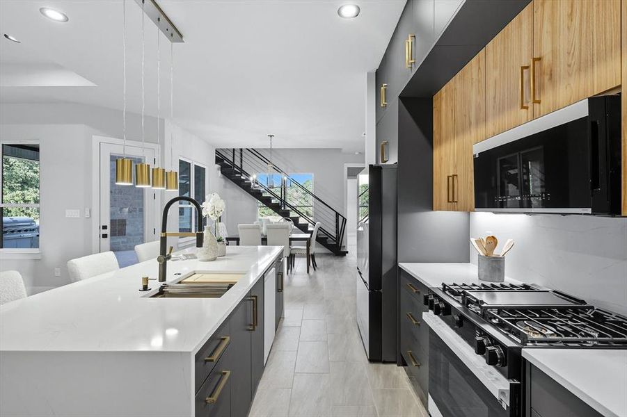 Kitchen with black appliances, modern cabinets, decorative light fixtures, light stone counters, and a breakfast bar Kitchen with black appliances, modern cabinets, decorative light fixtures, light stone counters, and a breakfast bar