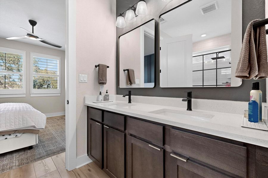 Ensuite bathroom featuring light wood finished floors, double vanity, and ceiling fan