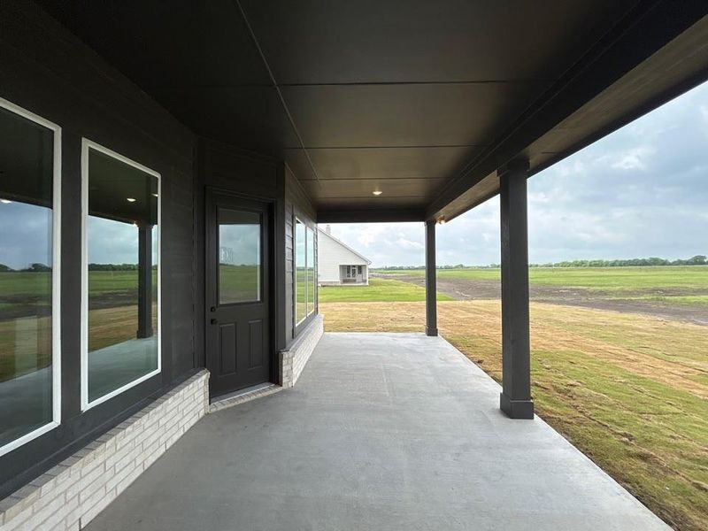 Covered patio featuring concrete flooring and dark-toned structural columns